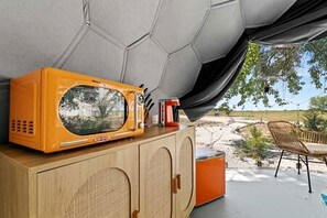 A room with a wooden cabinet, a vintage orange television, and a view of a desert landscape.