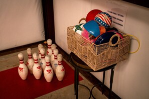 Ett rum med en röd matta, en skylt som hänger på väggen och en korg av rotting som innehåller bowlingbollar och ett blått föremål.