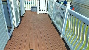A wooden deck with railings and a shadow of a person. - Lyons Sunnysands Holiday Park - Holiday Accommodation 20099 (Talybont)