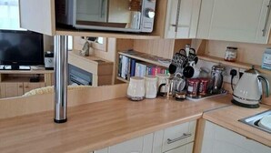 A compact kitchen with a microwave, kettle, and various kitchen utensils. - Lyons Sunnysands Holiday Park - Holiday Accommodation 20099 (Talybont)