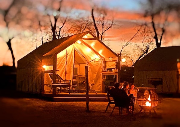 A tented accommodation with a dining area and a fire pit.