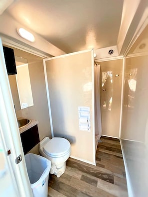 A compact bathroom with a toilet, sink, and mirror.