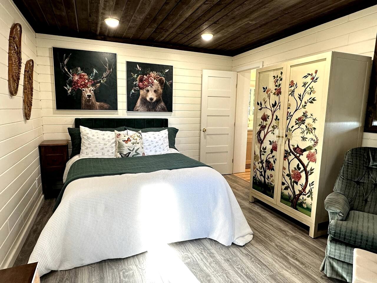 A bedroom with a bed, a wardrobe, and two wall-mounted paintings.