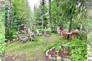 Ein bewaldeter Hinterhof mit Gartenmöbeln, einer Holzterrasse und einem Gartenbereich.