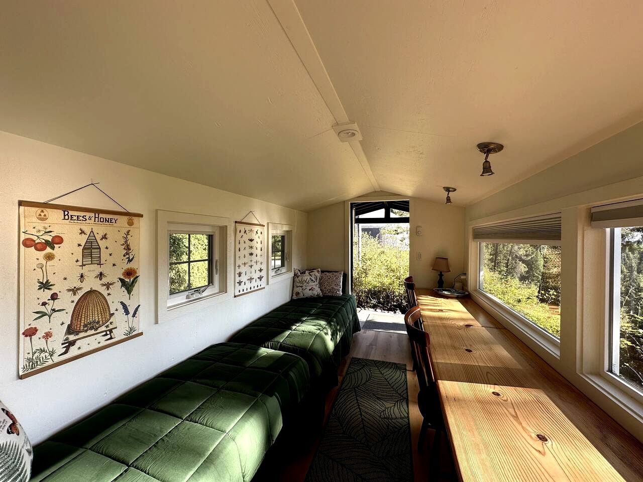 A room with a long green sofa, a wooden bench, and a window with a view of greenery.