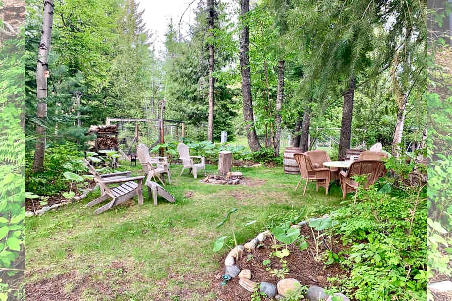A forested backyard with outdoor furniture, a wooden deck, and a garden area.