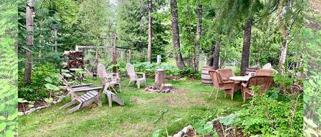 A forested backyard with outdoor furniture, a wooden deck, and a garden area.