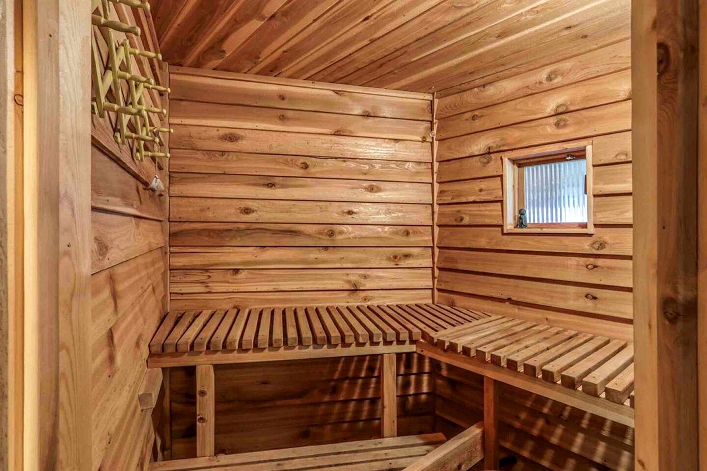 A wooden sauna with a bench, a window, and a wooden wall.