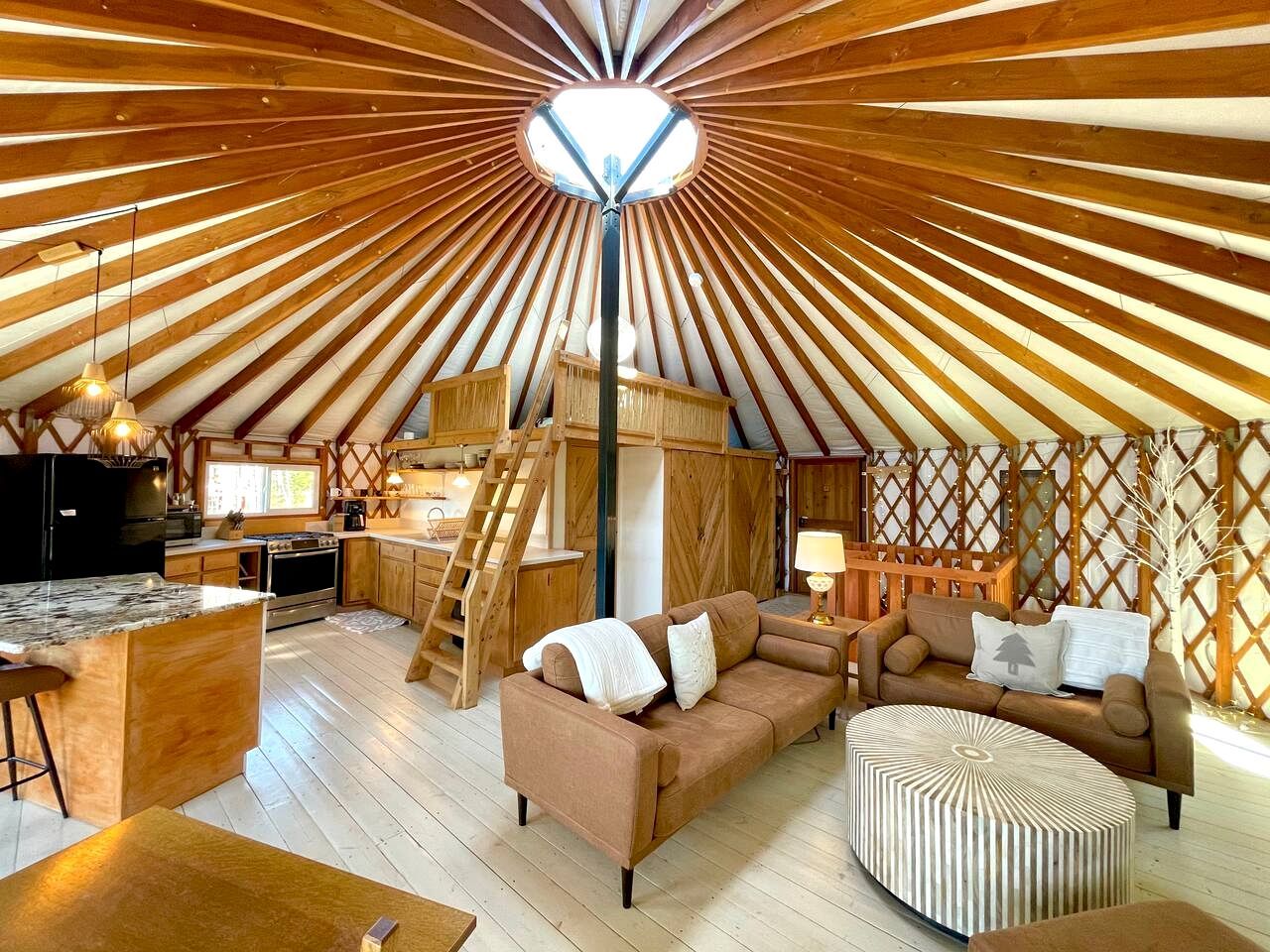 A cozy interior with a central wooden ceiling, a sofa, a coffee table, and a kitchen area.
