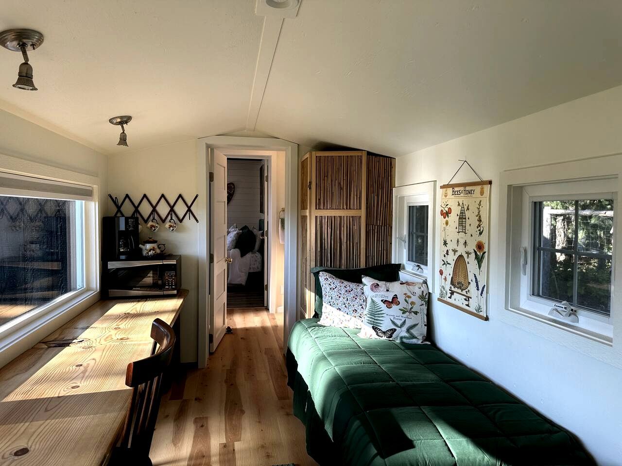 Una habitación pequeña con cama, una kitchenette compacta, una ventana y una puerta que da a otra habitación.
