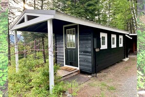 A small cabin with a porch, a door, and a window.