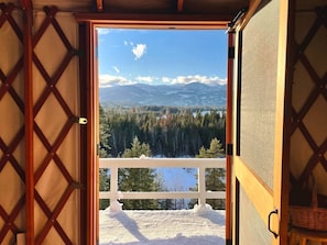 A room with a view of a snowy landscape and mountains.