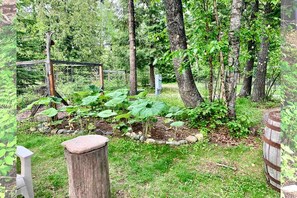 Een tuin met bomen, een houten hek en een stenen bank.