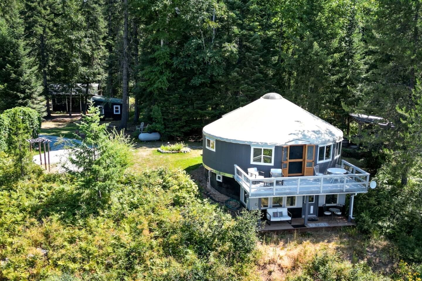 A dome-shaped house with a deck, surrounded by dense forest.