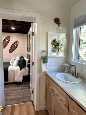 Un baño moderno con lavamanos, tocador y ventana.
