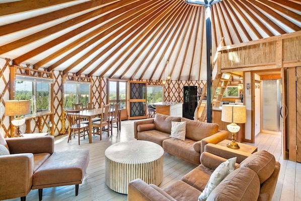 A yurt interior with a dining area, sofas, and a kitchen.