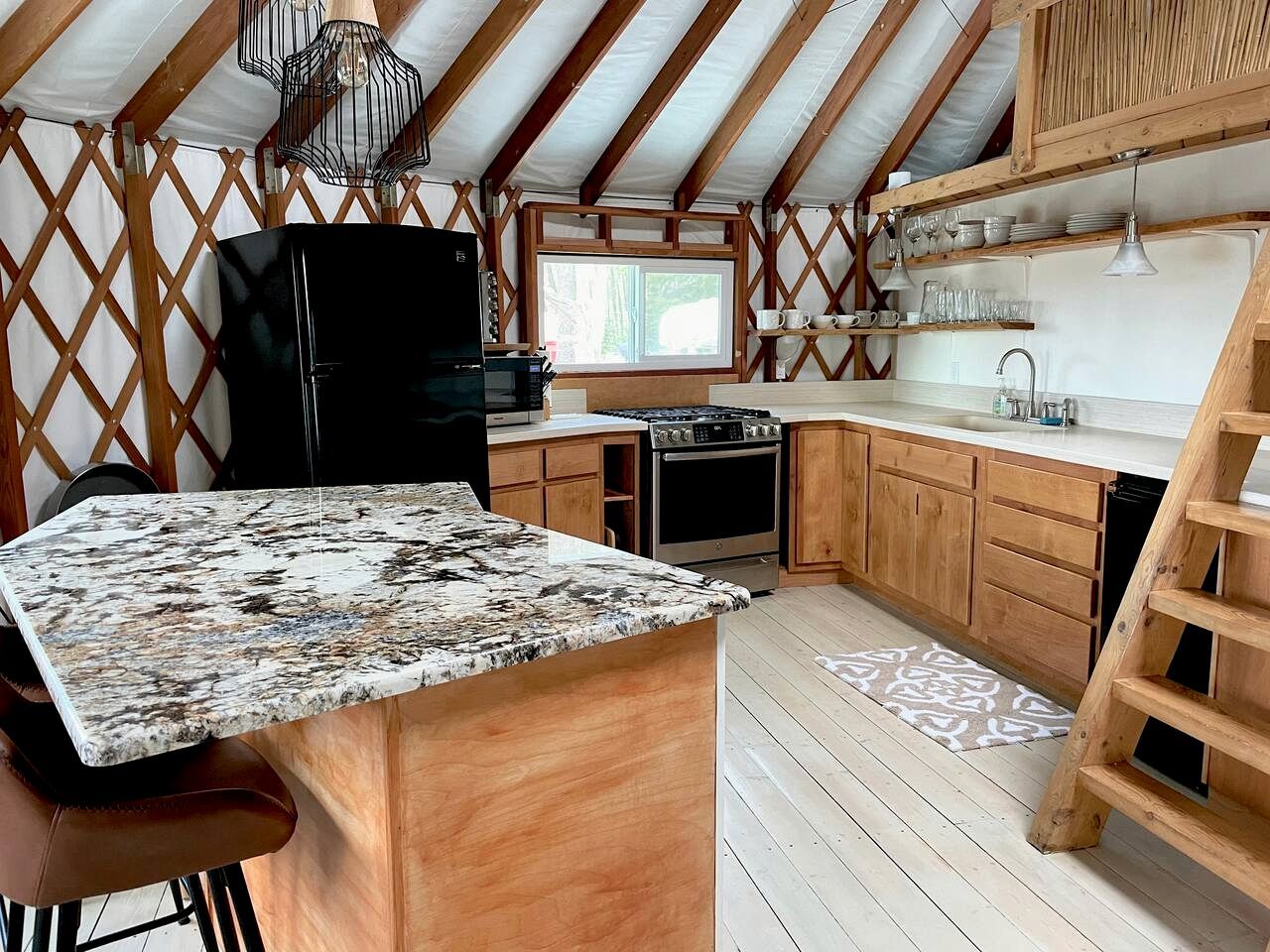 A compact kitchen with a central island, wooden cabinets, and a black refrigerator.