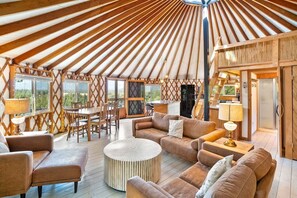 Interior de una yurtas con comedor, sofás y cocina.
