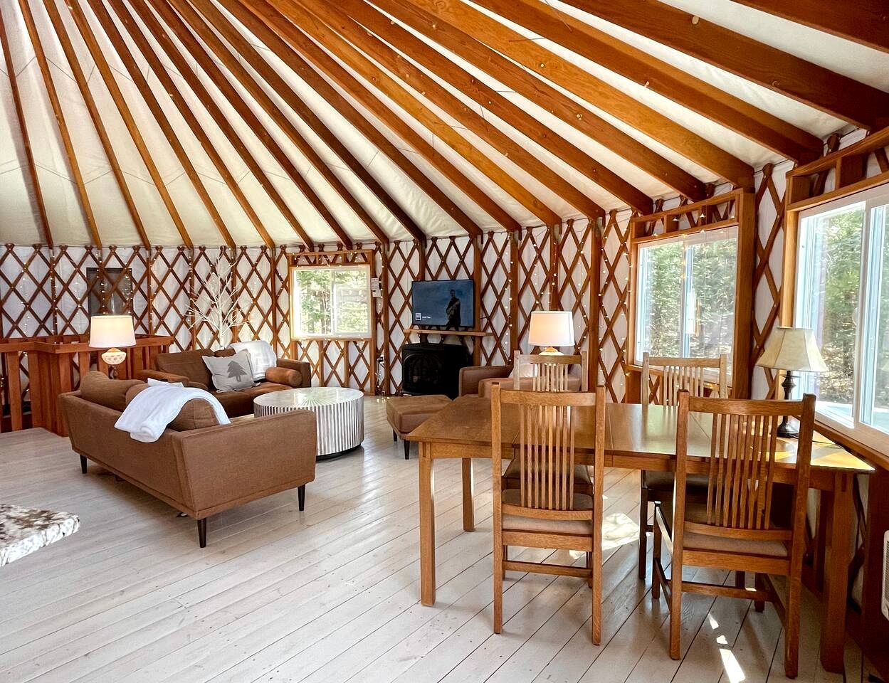 A cozy interior with a wooden ceiling, a sofa, a dining table, and chairs.