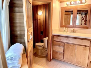 Een houten badkamer met toilet, wastafel en een badkamermeubel.