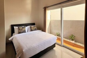 Ein Schlafzimmer mit einem Bett, einem Fenster und Blick auf einen Balkon.