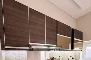 Eine moderne Küche mit dunklen Holzschränken, einer Edelstahl-Dunstabzugshaube und einem Fenster, das für natürliches Licht sorgt.