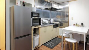 Une cuisine compacte équipée d’un réfrigérateur, d’un four à micro-ondes, d’une cuisinière et d’une machine à café posée sur le plan de travail.