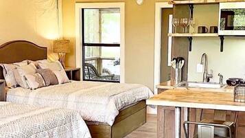 A tented accommodation with two beds, a kitchen area, and a view of the outside.