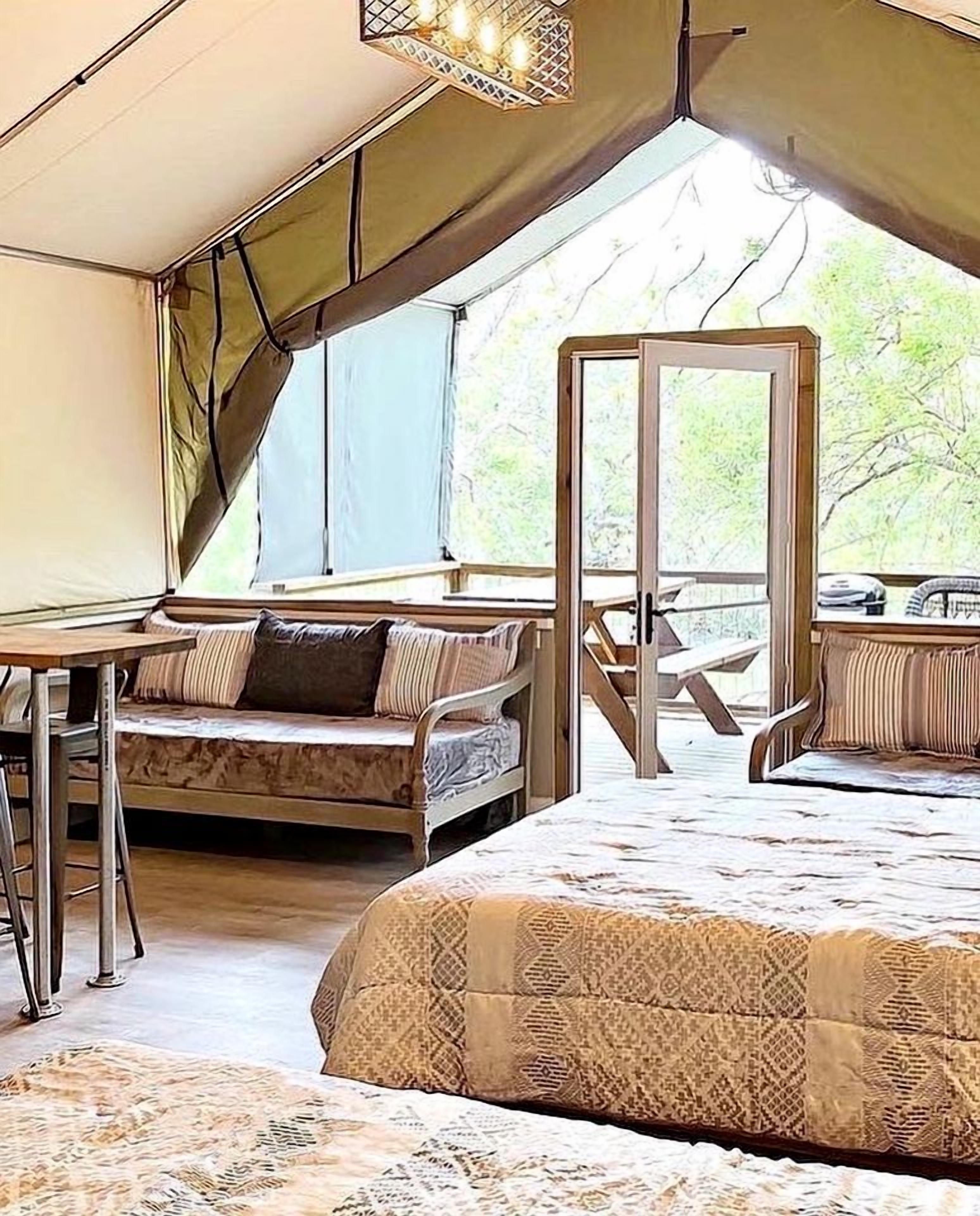 Une pièce aménagée avec une tente, un lit, une table et une chaise.