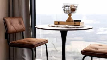 Una habitación moderna con vistas, que incluye una mesa redonda con un candelabro, dos sillones tapizados y una alfombra a cuadros.