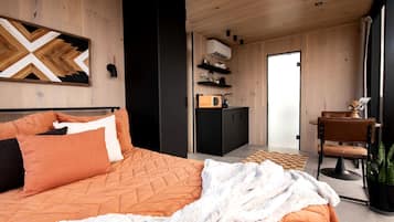 Un dormitorio moderno con una cama grande, un armario negro, una kitchenette y vistas al exterior.