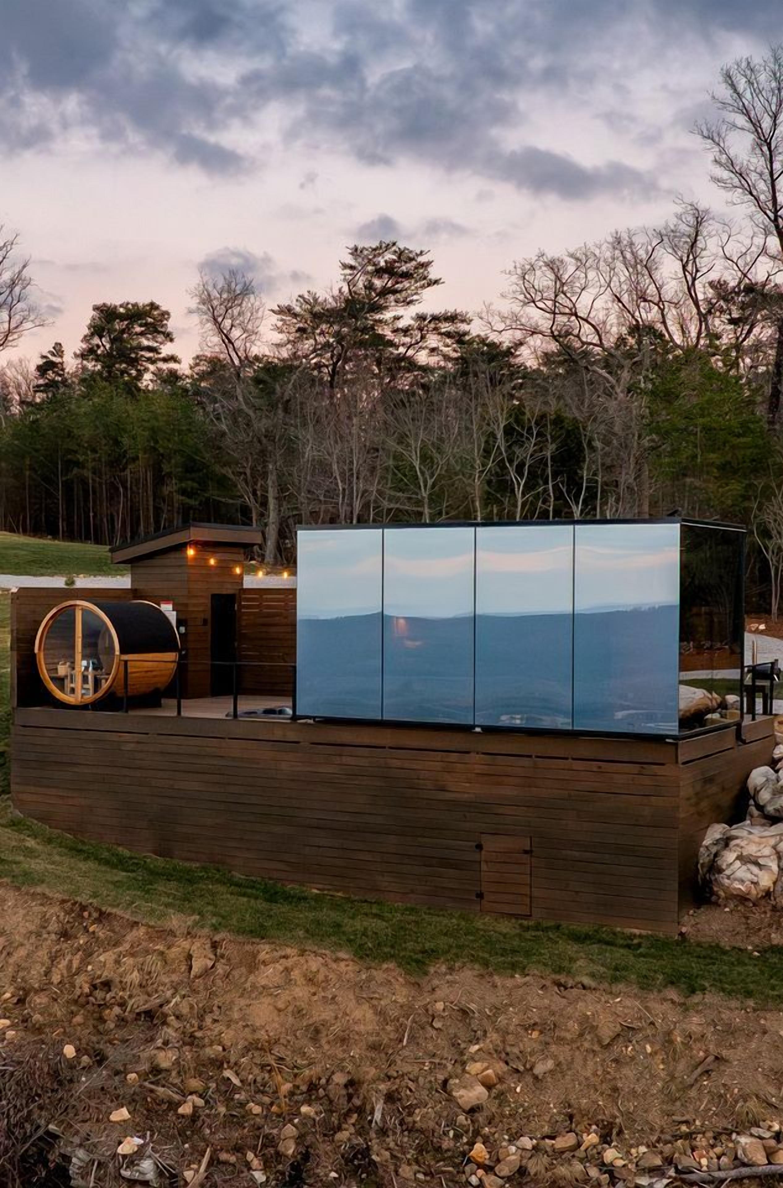 A cabin with a large glass wall, a wooden deck, and a circular skylight.