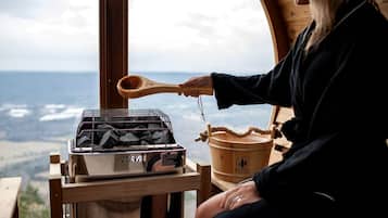 A person cooking outdoors with a charcoal grill, a wooden spoon, and a bucket.