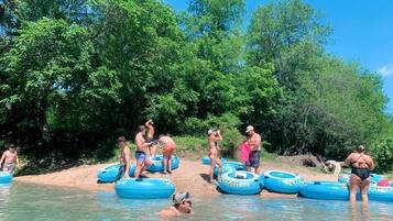 People in a natural setting with water, trees, and inflatable rings.