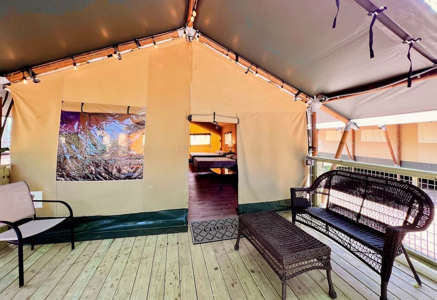 A tent with a bed, a bench, and a welcome mat.