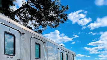 A row of mobile homes with external shower facilities, metal stairs, and a dirt ground.