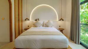 A bedroom with a large bed, two bedside tables, a circular light fixture above the bed, and a view of greenery through a window. - Stunning 3BR Villa • Rooftop Pool • 3min to Beach Balangan (Badung)