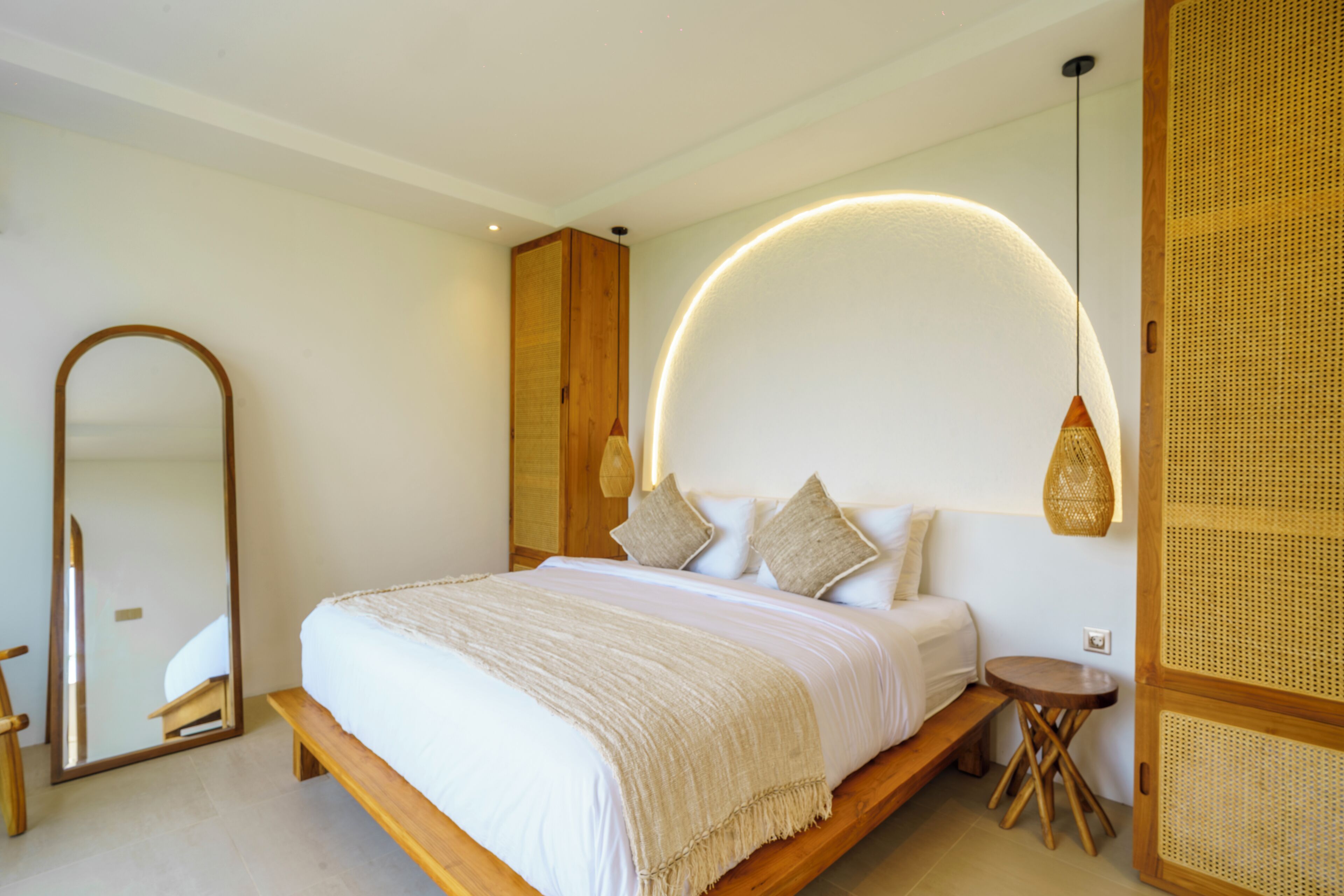 Un dormitorio con una cama, un espejo, una mesita de noche y una lámpara fijada a la pared.
