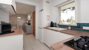 Una cocina moderna con estufa integrada, refrigerador y ventana con vistas al exterior.