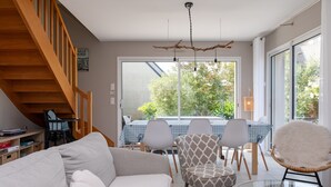 Una sala de estar moderna con un sofá, una mesa de comedor, sillas y una escalera.