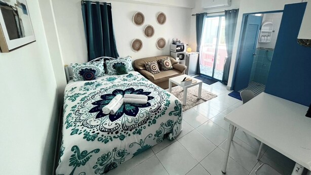 Une chambre à coucher comprenant un lit, un canapé, une petite table, un bureau et une salle de bain avec douche.