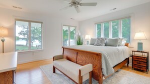 Une chambre à coucher comprenant un lit, un banc, une table de chevet et un ventilateur de plafond.