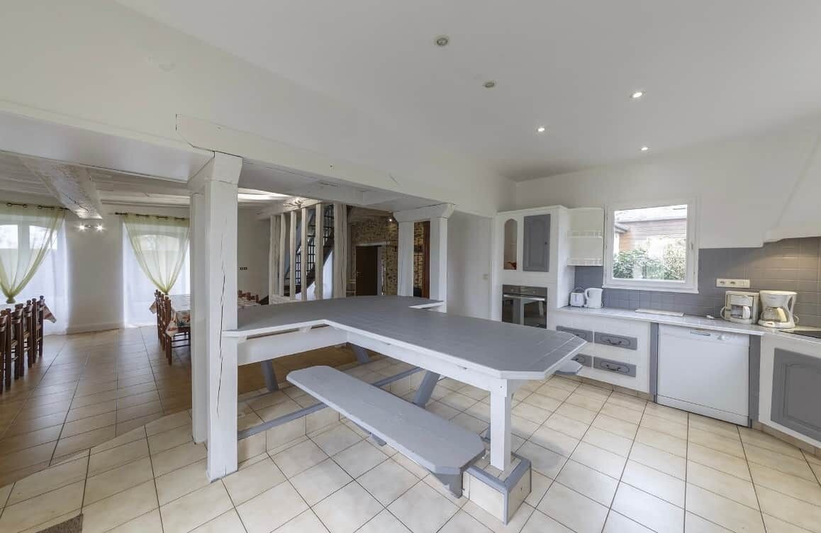 A spacious kitchen with a large dining table, a built-in oven, and a window overlooking the garden.