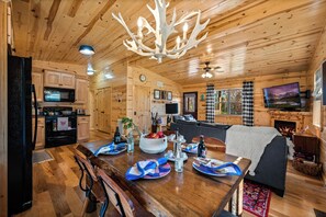 Ein Holzblockhaus-Interieur mit Essbereich, Küche, Wohnzimmer und Kamin.