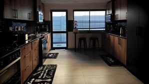 A modern kitchen with wooden cabinets, a stove, and a large window.