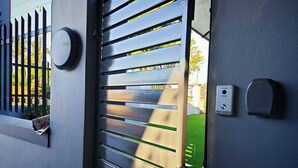 A modern door with horizontal slats, a round sensor, and a rectangular device on the wall.