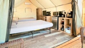 Una tenda con un letto, angolo cottura e una sedia in vimini.