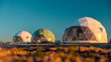 Three geodesic dome structures with a clear sky in the background.