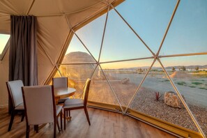 Tienda de campaña con zona de comedor y vista a un paisaje desértico.
