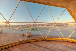 Estrutura em forma de cúpula geodésica com vista para uma paisagem desértica.